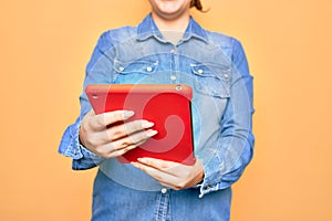 Young caucasian woman working using tablet standing over isolated yellow background