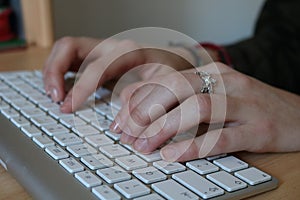 Young caucasian woman writing on a white computer keyboard