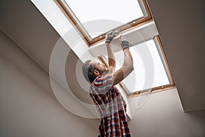 Young caucasian worker screwing skylight window handle