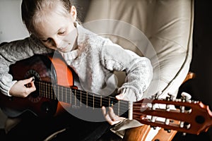 A young caucasion girl practicing playing her guitar