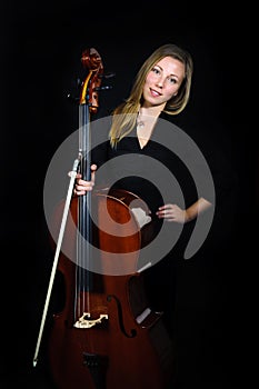Young cellist standing on black background