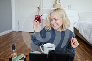 Young charismatic beauty blogger, teenage girl records video of her applying mascara, reviewing makeup products for her