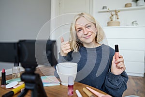 Young charismatic beauty blogger, teenage girl records video of her applying mascara, reviewing makeup products for her