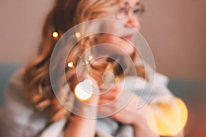 Young charming blonde woman in glasses with lights in her hair, romantic atmospheric photo about dreams, blurred focus