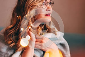 Young charming blonde woman in glasses with lights in her hair, romantic atmospheric photo about dreams, blurred focus