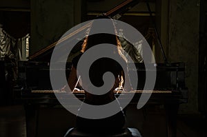 Young charming brunette girl playing the piano