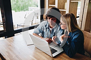 Young charming couple using laptop while sitting at cafe