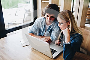 Young charming couple using laptop while sitting at cafe