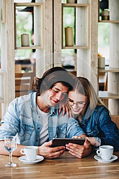 Young Charming Couple Using Tablet While Sitting Together And Dr