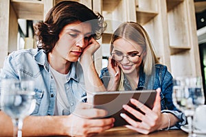 Young Charming Couple Using Tablet While Sitting Together And Dr