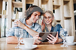 Young Charming Couple Using Tablet While Sitting Together And Dr