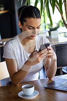 Young charming European woman calling with cell telephone during morning breakfast in coffee shop, beautiful female student having