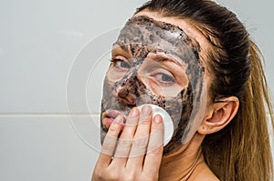 Young charming girl makes a black charcoal mask on her face