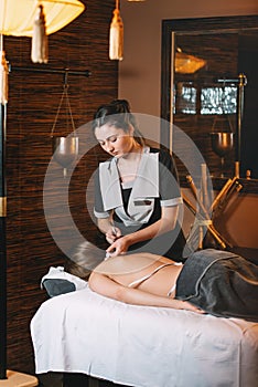 Young charming girl on a panchakarma procedure laying on a massage table. beautiful woman spending time at modern spa