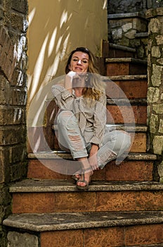 Young charming girl sitting on the old antique stone steps
