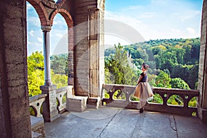 Young charming lady in vintage dress on the balcony of the castle