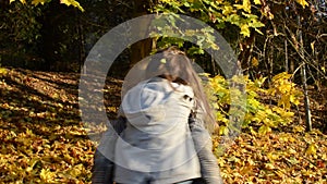 Young charming mother whirls holding her baby daughter in her arms among yellow fallen maple leaves, happy family