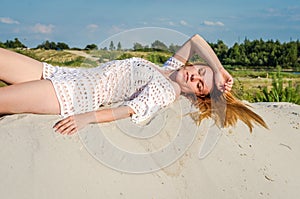 Young charming girl with long hair and make-up in bikini bathing suit, in an erotic pose lying and sunning on a sunny hot day