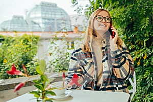 Young charming woman calling with cell telephone while sitting alone in coffee shop during free time, attractive female