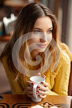 Young charming woman having coffee in a coffee shop