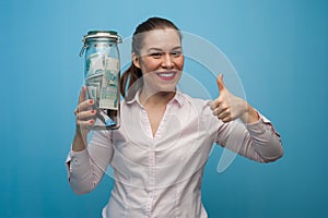 Young charming woman holds a jar with money