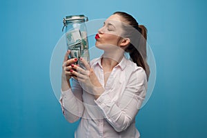 Young charming woman holds a jar with money