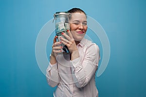 Young charming woman holds a jar with money