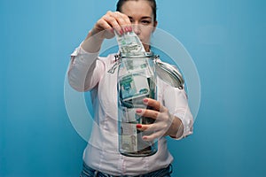 Young charming woman holds a jar with money