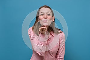 Young charming woman sending air kiss and looking at camera