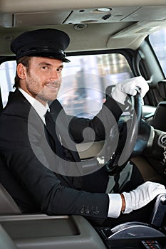 Young chauffeur in limousine smiling