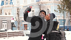 Young cheerful african couple taking selfie with smartphone and then checking it out