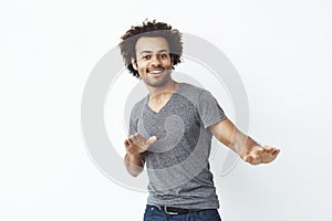 Young cheerful african man moving dancing looking at camera over white background.