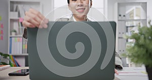 Young cheerful Asia professional businesswoman sitting on desk near window open laptop enjoy start work at office. Lady business