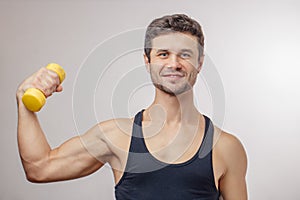 Young cheerful athlete is developing his muscles