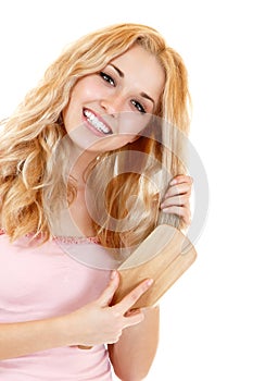 Young cheerful blond woman combing hair