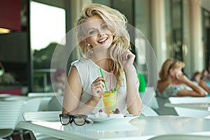 Young cheerful blonde in a drink bar