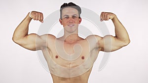 Young cheerful bodybuilder flexing his biceps, smiling to the camera