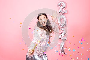 Young woman on a pink background with silver ballons in the form of the numbers 2021 photo