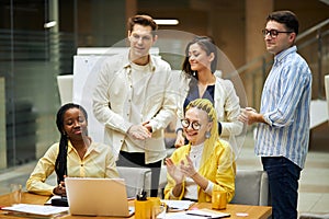 Young cheerful co-workers greeting their colleague