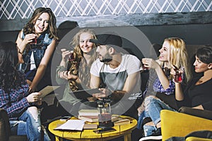 Young cheerful company of friends with mobile, tablet and tea co