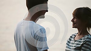 Young cheerful couple kissing on the beach. Happy man and woman spending time together on the nature on sunset.