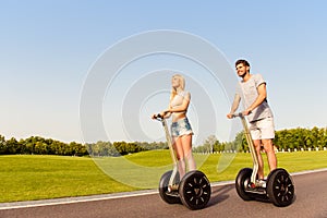 Young cheerful couple in love driving segways and smiling in park photo