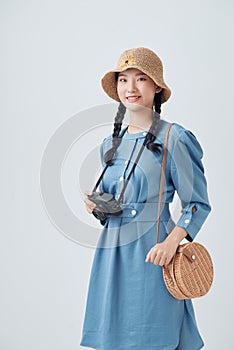 Young cheerful female tourist photographer is excited and holding camera, wearing hat on white background