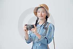 Young cheerful female tourist photographer is excited and holding camera, wearing hat on white background