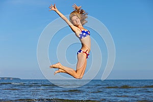 Young cheerful girl jumping at sea