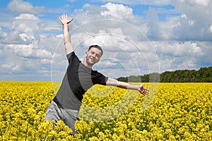 Young cheerful guy having fun in a yellow rapeseed field, happy life without allergy