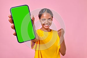 Young cheerful Indian woman holding smartphone and making victory gesture