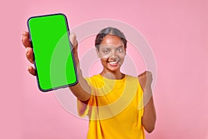 Young cheerful Indian woman student showing phone and making victory gesture