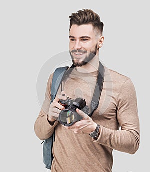 Young cheerful man photographer takes images with digital camera. Isolated on gray background photo