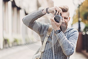 Young cheerful man photographer taking pictures with camera